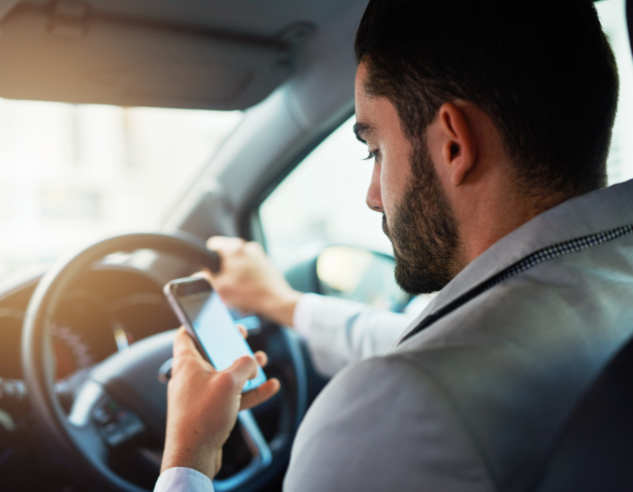 man holding phone and texting while driving