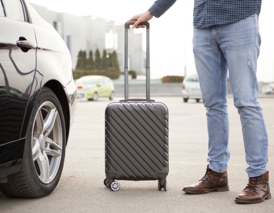 man with suitcase getting in rental car